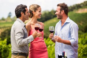 Men and woman holding a glass of red wine in a party